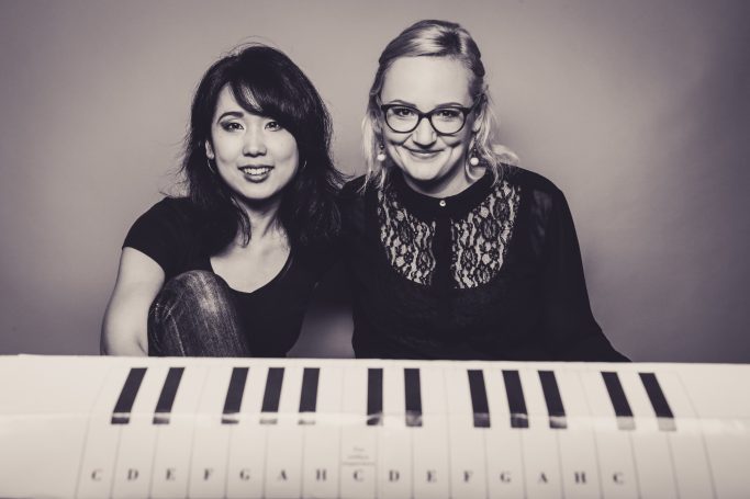 Mari Inoue und Katharina Sames lächeln in die Kamera, im Vordergrund eine Klaviertastatur