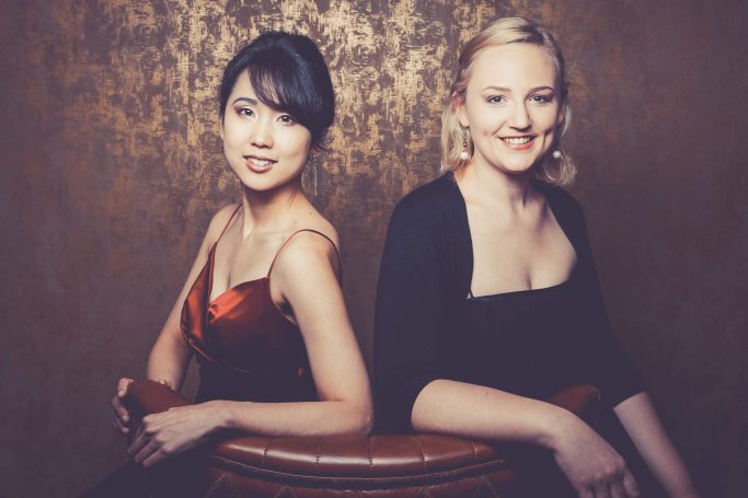 Mari Inoue und Katharina Sames sitzen in Abendkleidern auf einem Sessel